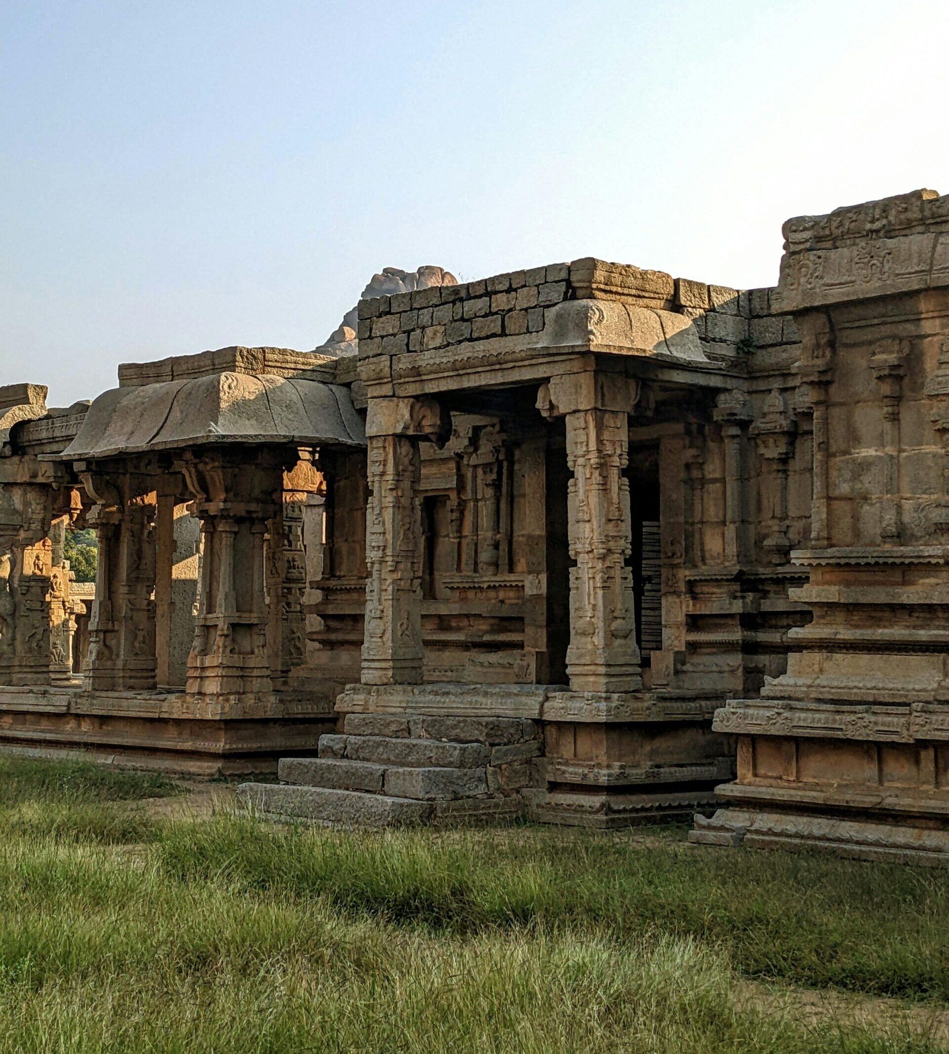 Beautiful view of ancient stone temple ruins surrounded by grass at sunrise.