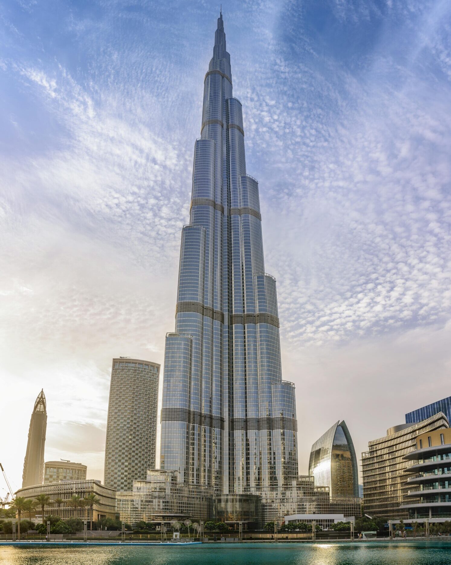 Majestic Burj Khalifa against a bright blue sky reflecting in water, Dubai.