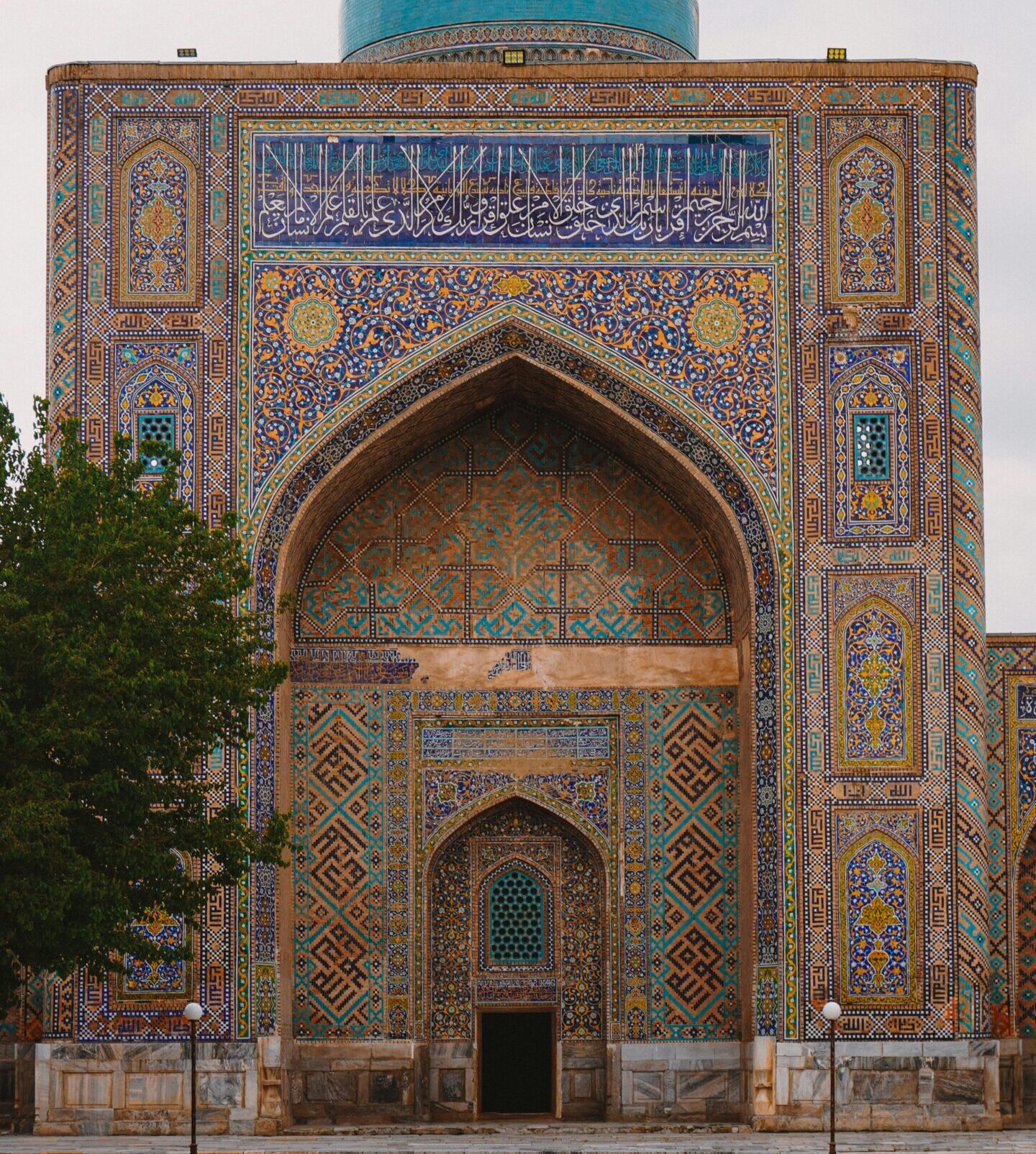 Intricate architectural facade of a mosque in Samarkand, showcasing rich patterns and a prominent turquoise dome.