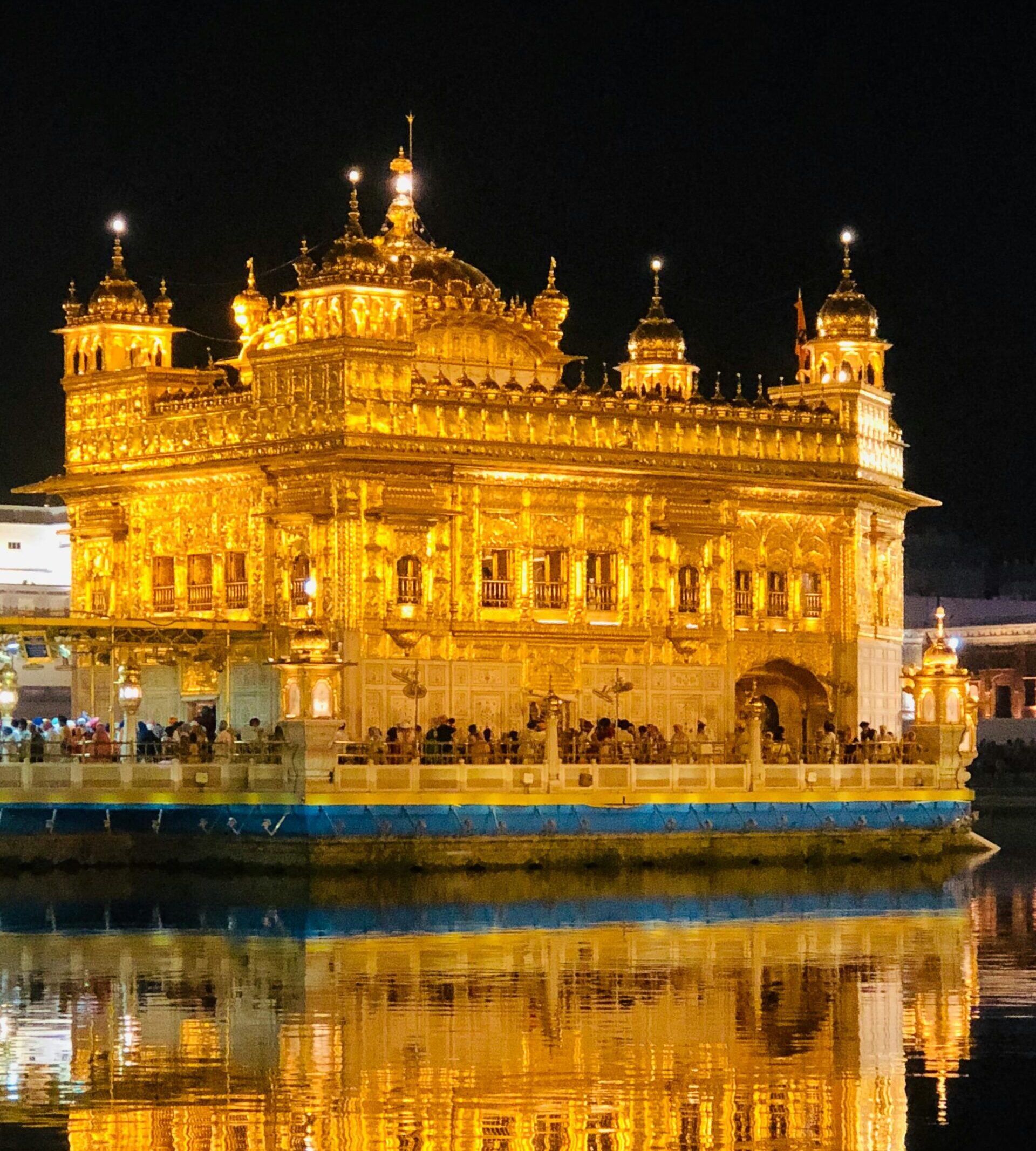 Breathtaking night view of the illuminated Golden Temple in Amritsar, India with reflection in water.