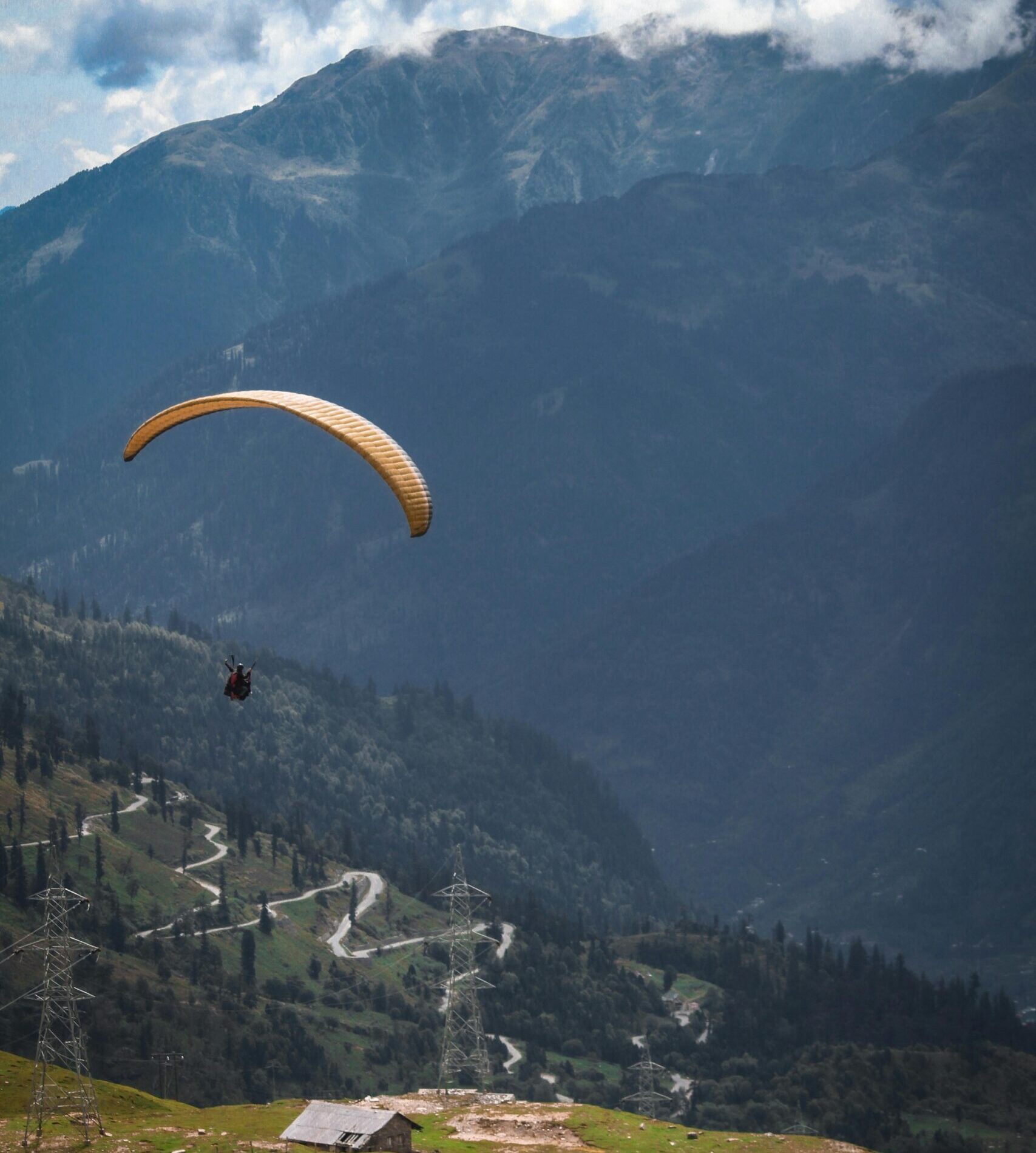 Experience the thrill of paragliding over picturesque hills and valleys in Manali, India.
